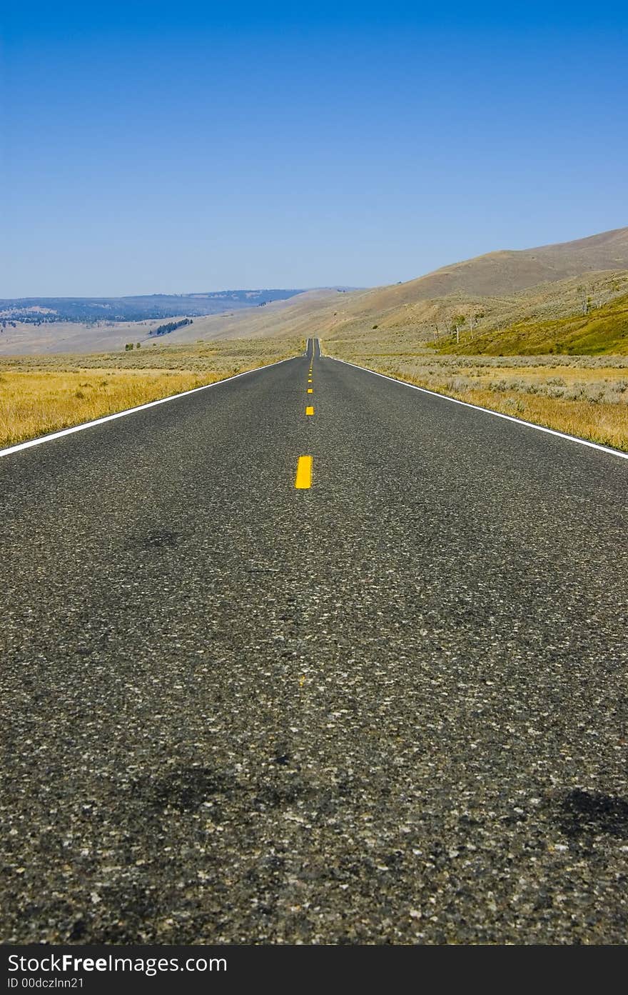 The road leading through the open space of Lamar Valley in Yellowstone National Park. The road leading through the open space of Lamar Valley in Yellowstone National Park