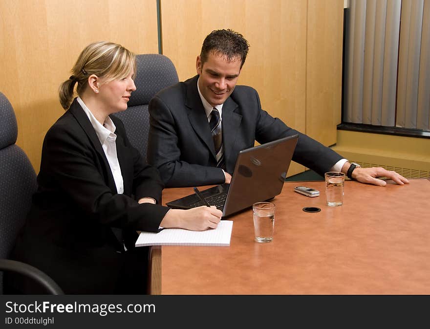 Business colleagues in a board room with a laptop. Business colleagues in a board room with a laptop