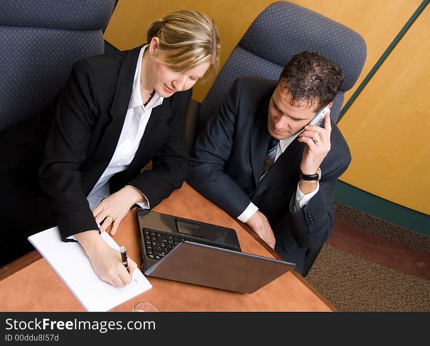 Business colleagues in a board room with a laptop and phone. Business colleagues in a board room with a laptop and phone