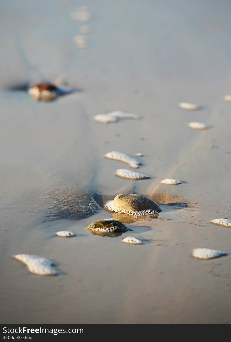 Wet stones in the foam on seacoast