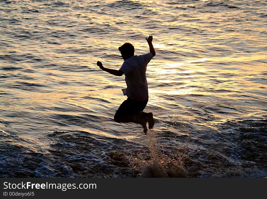 Silhouette of boy jumping in the ocean at sunset. Silhouette of boy jumping in the ocean at sunset