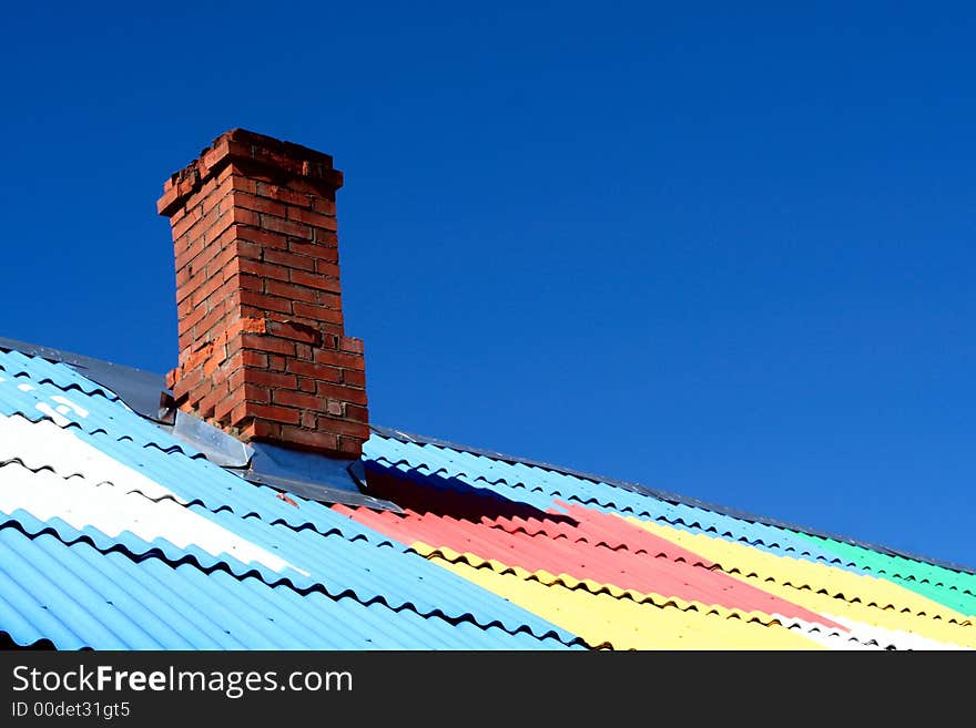 Chimney on colored roof under blue sky