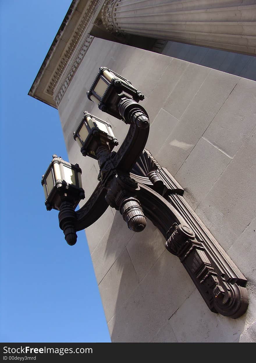 Old ornate decorative brass lamp with three heads on old building in London. Old ornate decorative brass lamp with three heads on old building in London