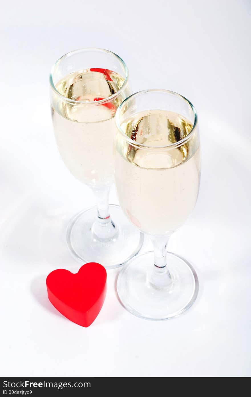 Two glasses of champagne and red plastic heart. Two glasses of champagne and red plastic heart