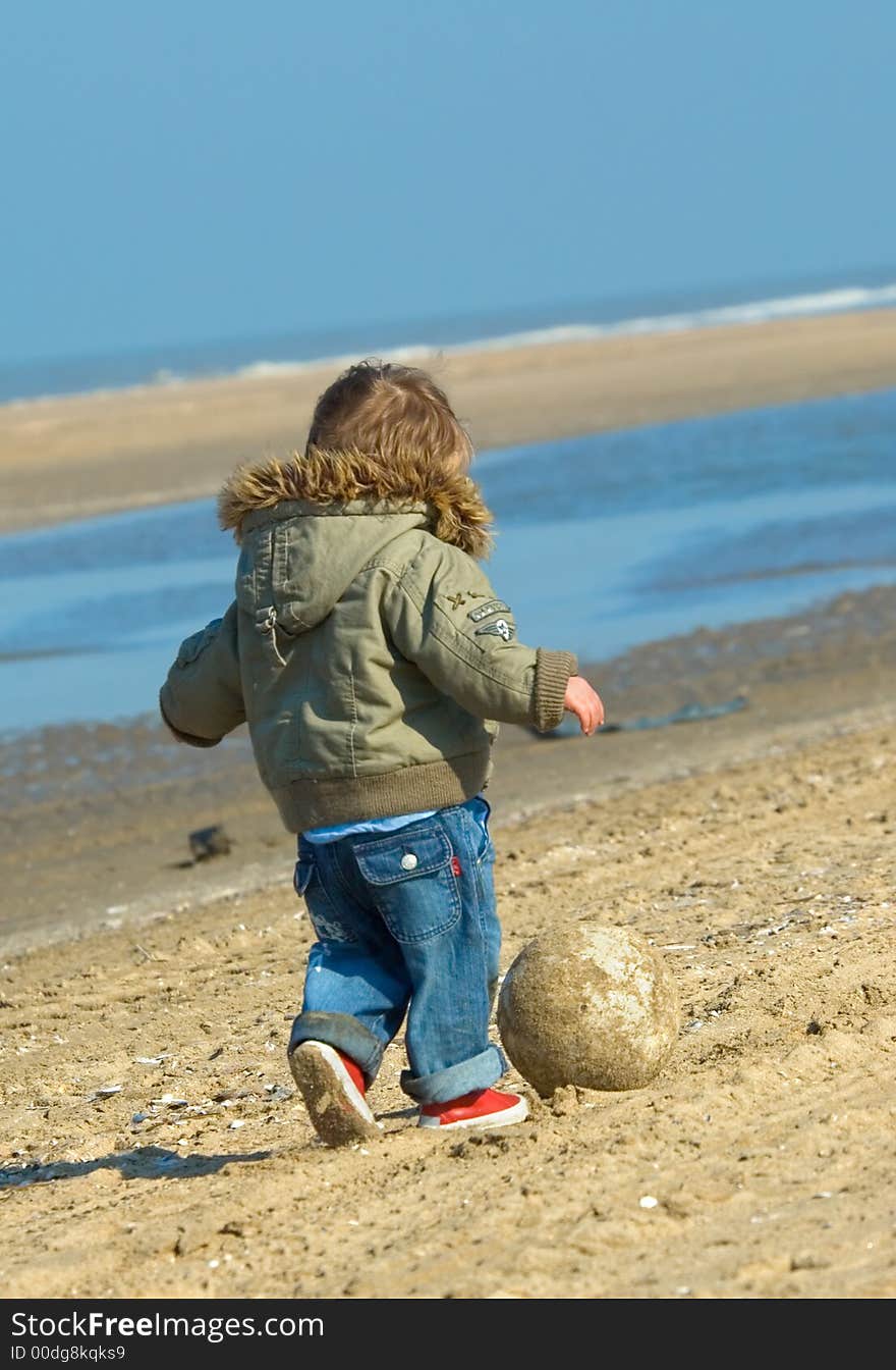 Cute boy playing soccer on the beach