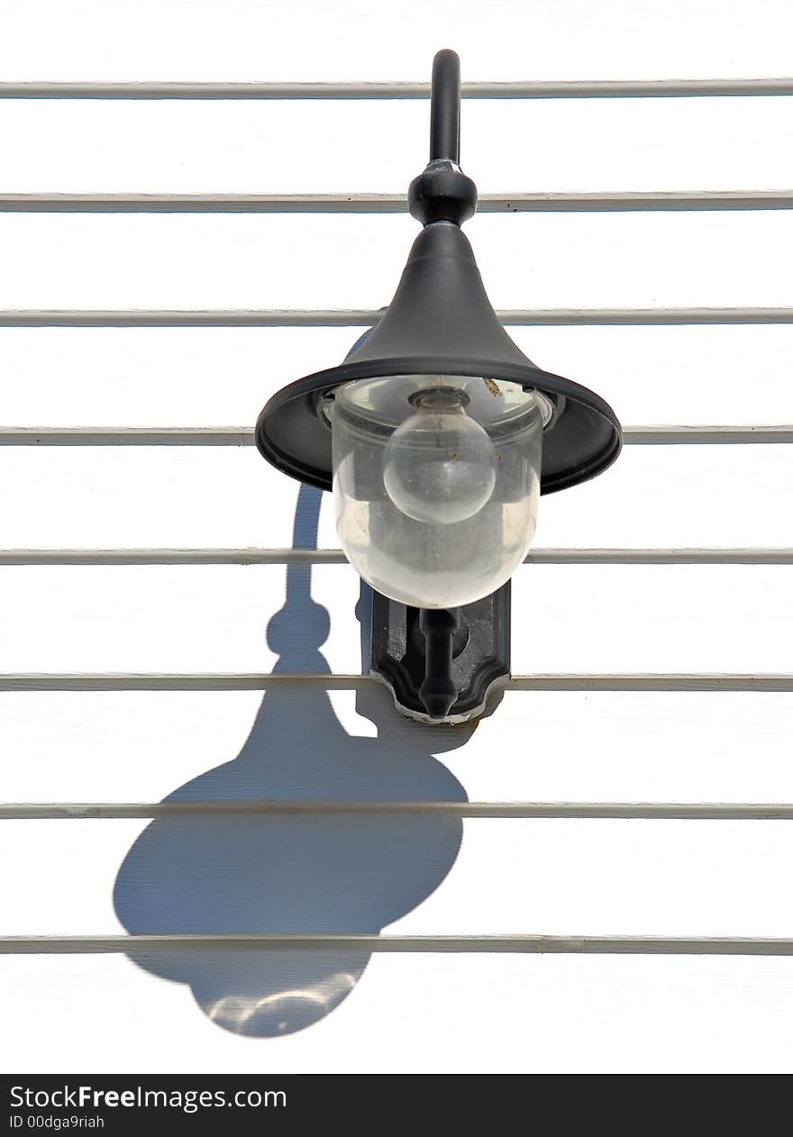 Lantern and its shadow on a white wooden wall