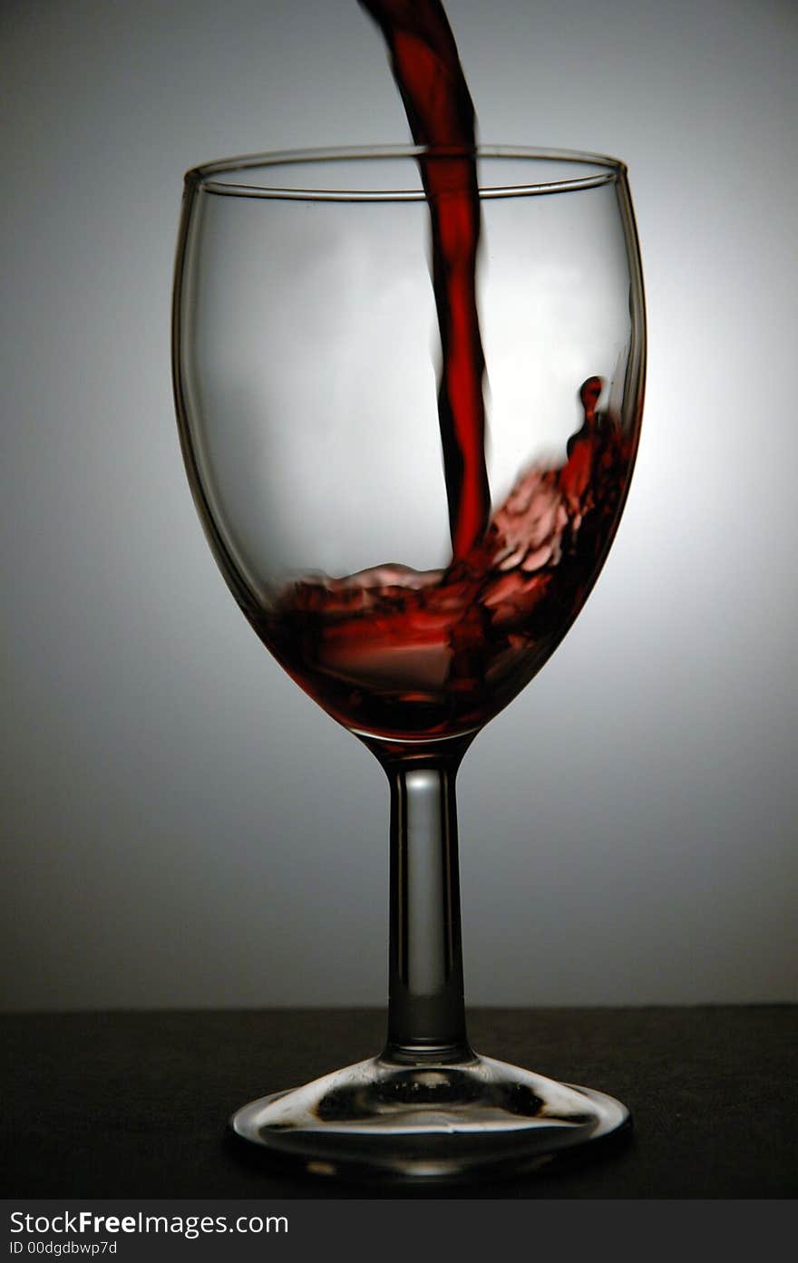 Red wine being poured into a glass. Low key image taken in a studio. Red wine being poured into a glass. Low key image taken in a studio.