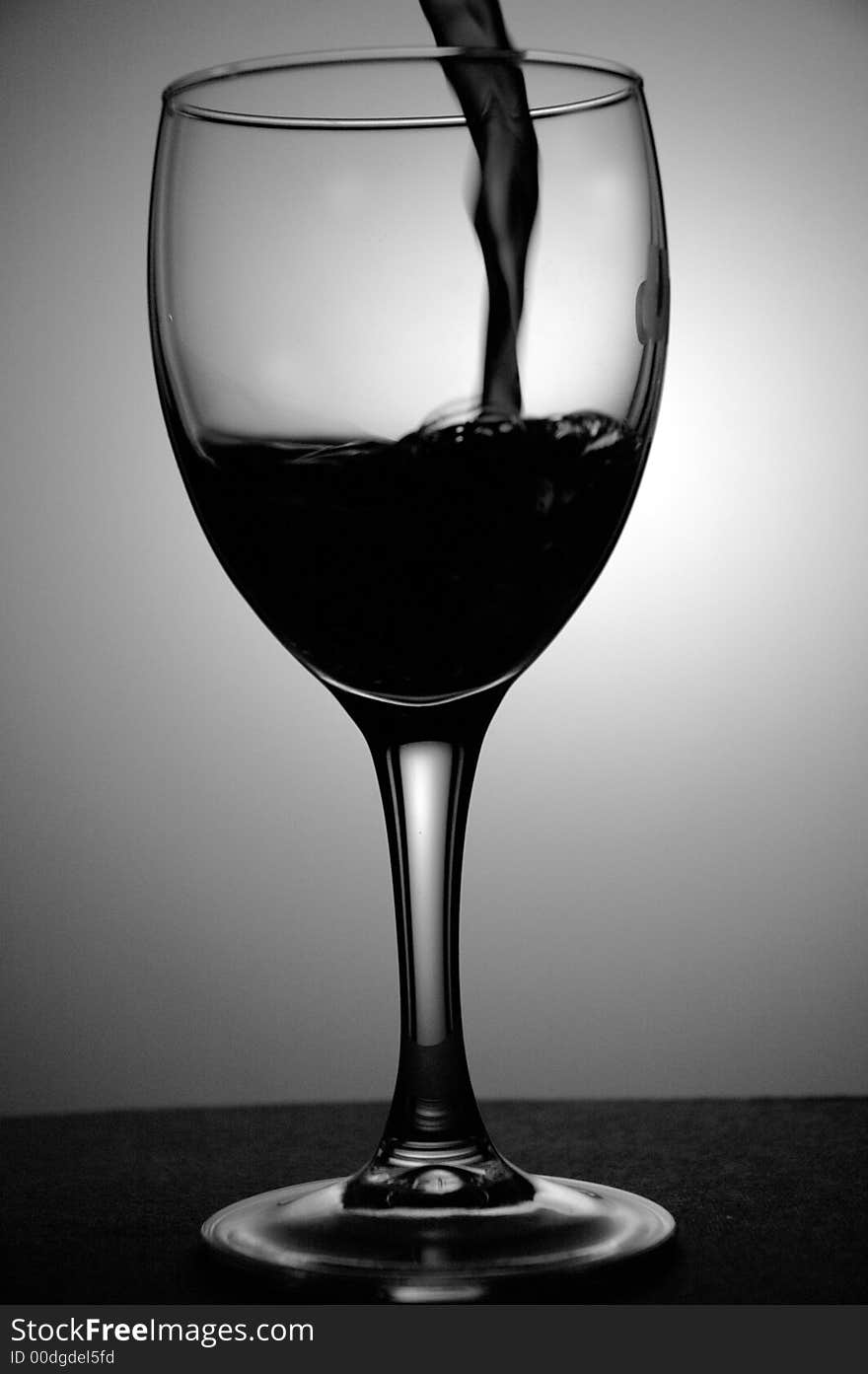 Red wine being poured into a glass. Low key image taken in a studio. Red wine being poured into a glass. Low key image taken in a studio.