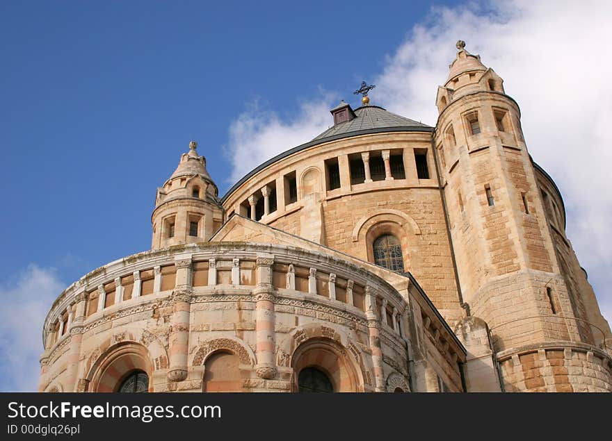 Dormition Abby (Benedictine Basilica of the Dormition) in Jerusalem. The Dormition Abbey is a massive structure, just outside the Zion Gate, and resembles a mighty fortress; it is topped by a high, domed belltower, a conical dome and corner towers.