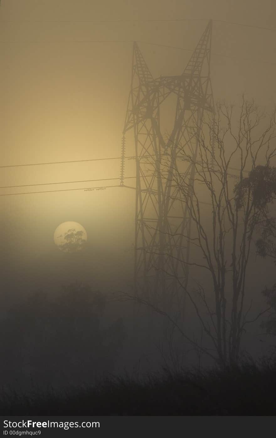 An electrical power pylon with powerlines is depicted in a foggy sunrise. An electrical power pylon with powerlines is depicted in a foggy sunrise.