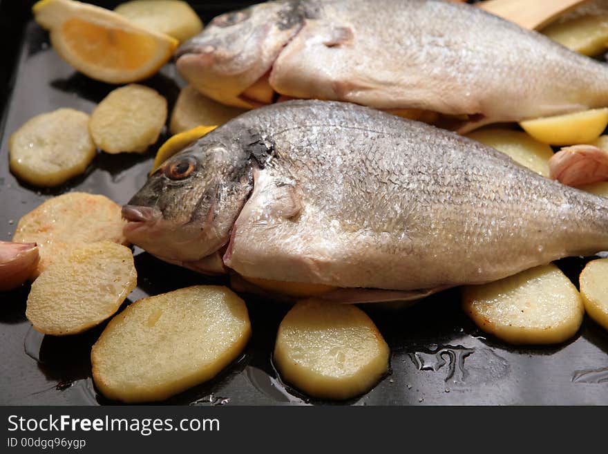 Gilthead Bream fish with potato slices in a oven tray for cook