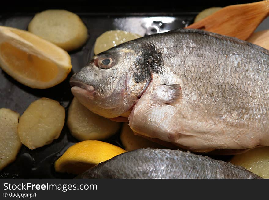 Gilthead Bream fish with potato slices in a oven tray for cook