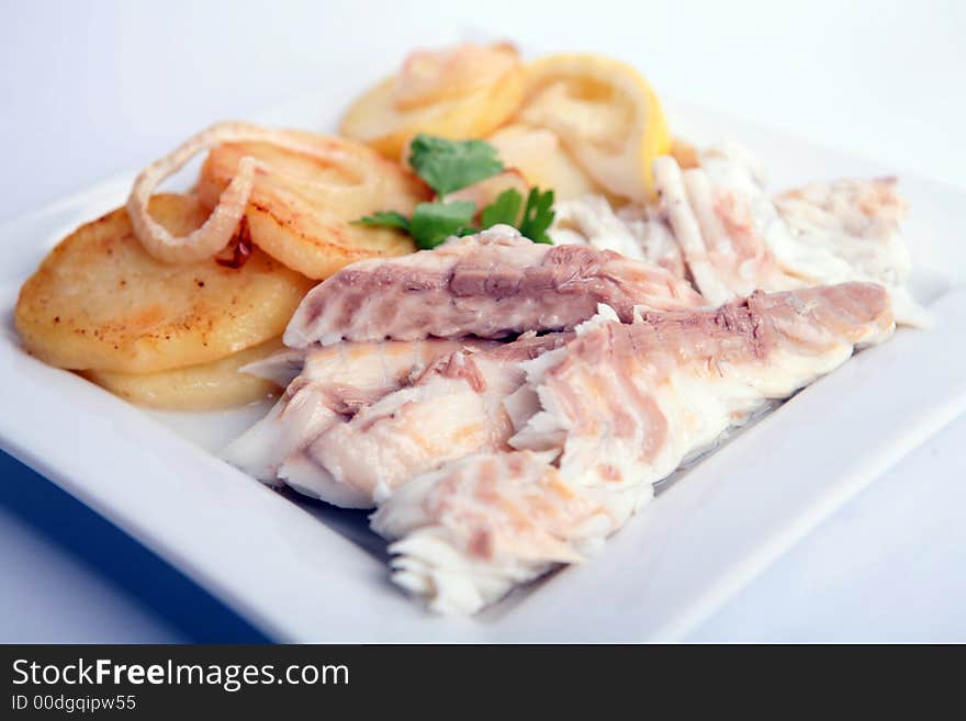 Gilthead Bream fish cooked with potato slices in a white dish