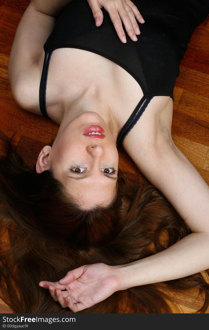 A woman, lying on her back on a wooden floor. A woman, lying on her back on a wooden floor