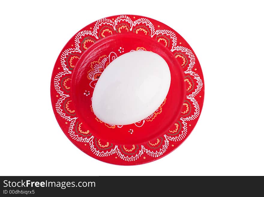 One white egg on a painted red plate. One white egg on a painted red plate.