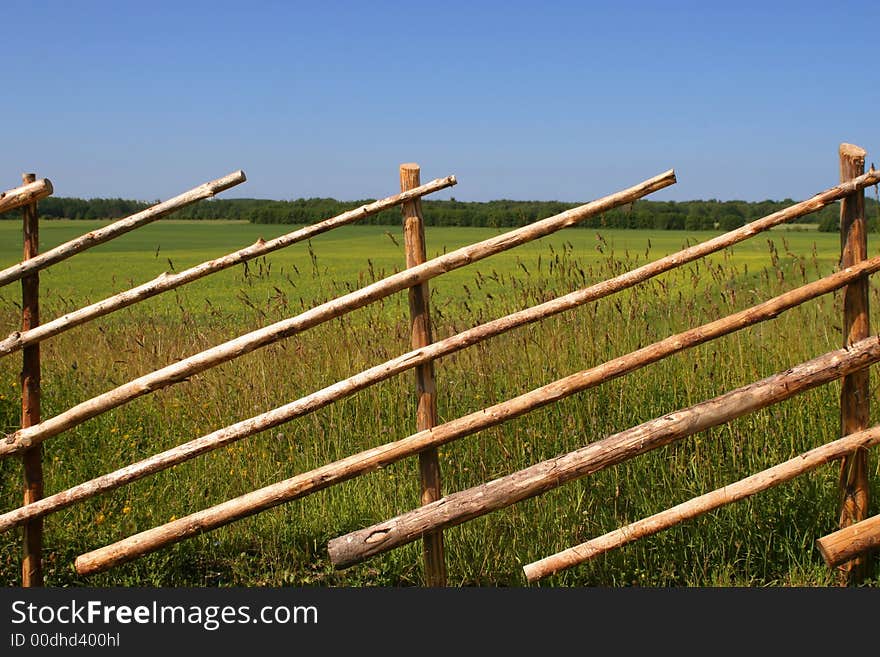 Old wooden fence near big yellow field