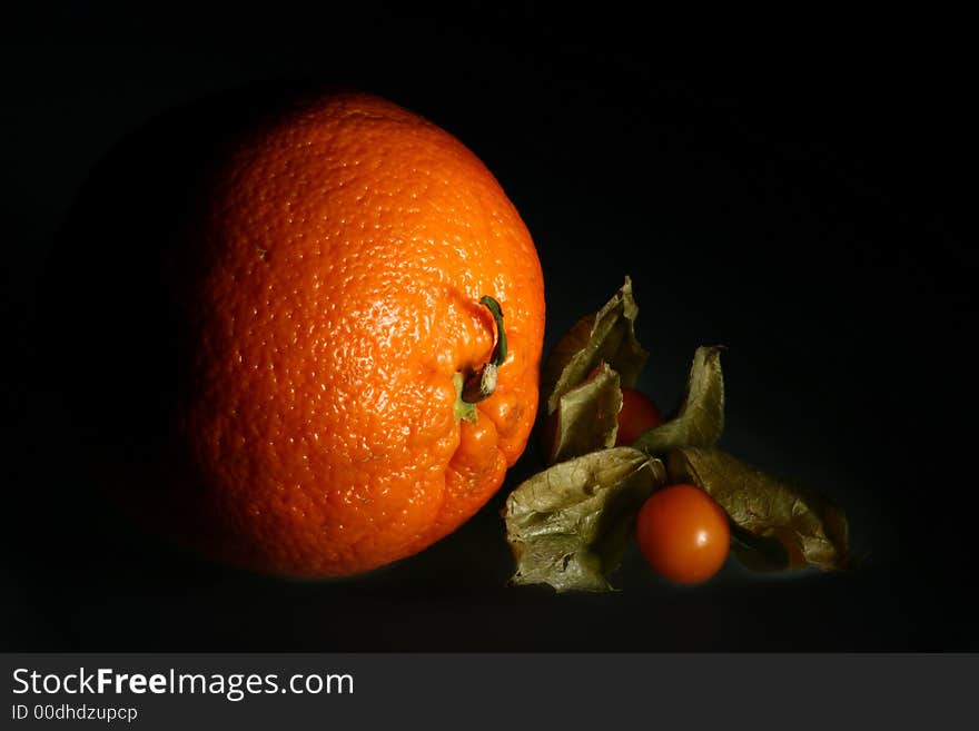 Small ripe goldenberry and big ripe orange. Small ripe goldenberry and big ripe orange