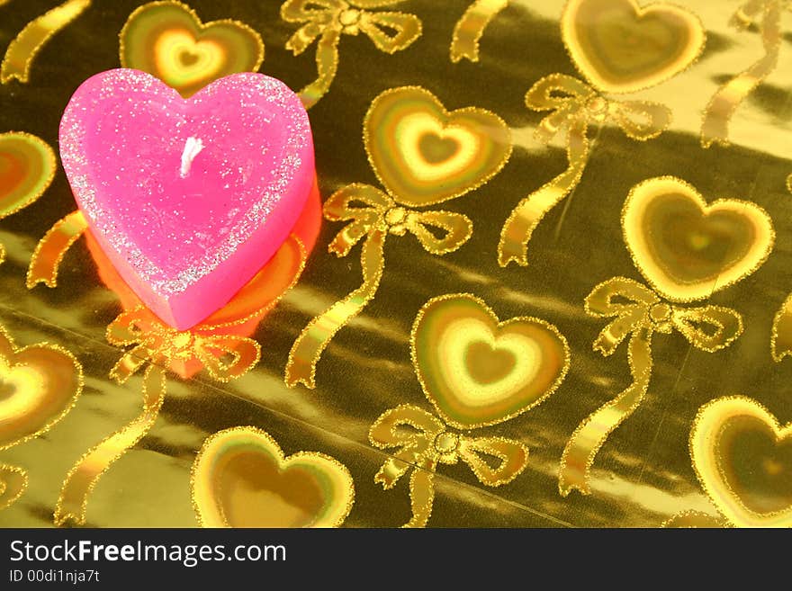 Candle in the form of heart on a golden background