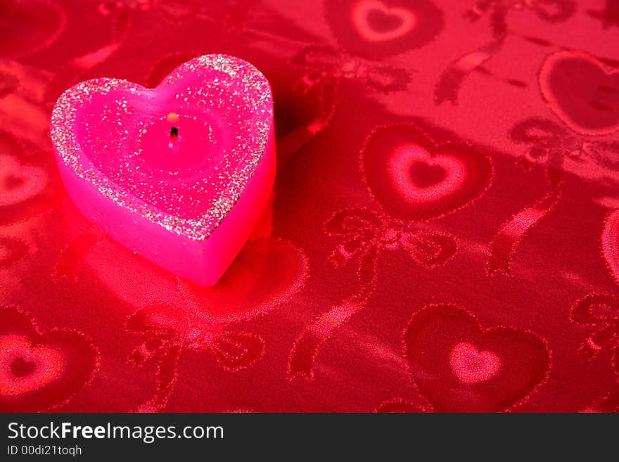 Candle in the form of heart on a red background