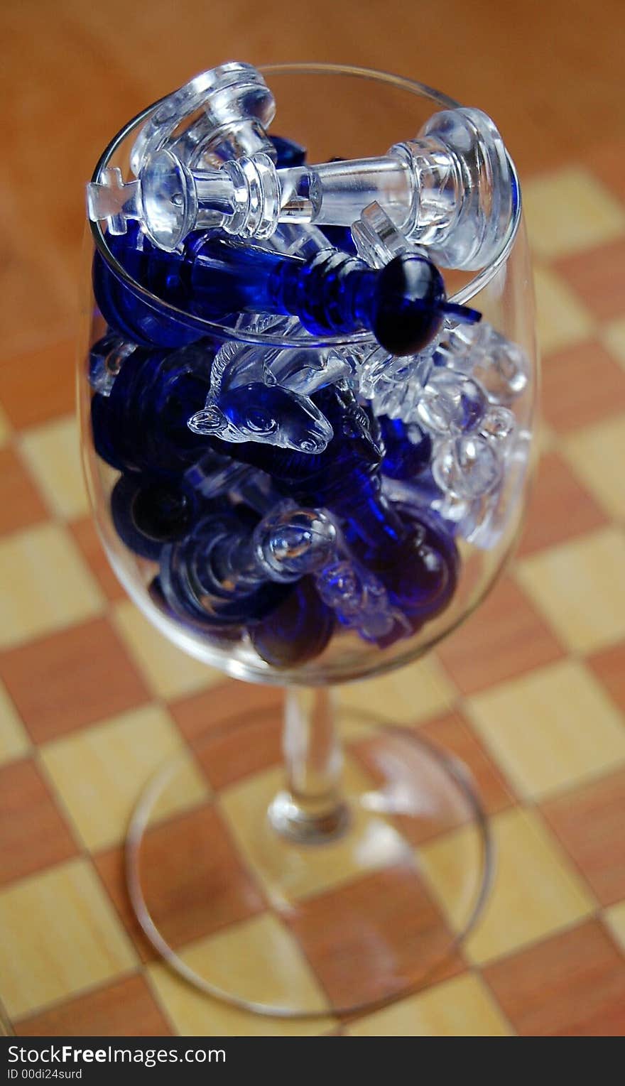 Wine glass with chess pieces inside stending on the chessboard. Wine glass with chess pieces inside stending on the chessboard