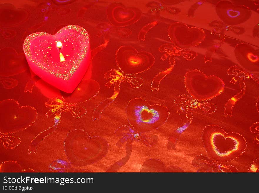 Candle in the form of heart on a red background