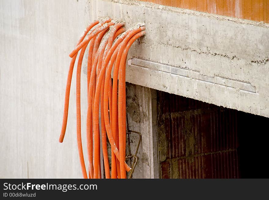 Orange pipes coming out of a raw concrete wall. Orange pipes coming out of a raw concrete wall.