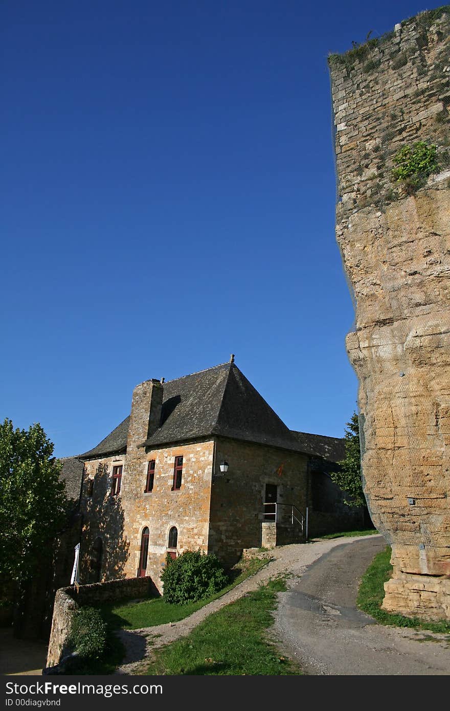 Large natural stone wall overlooking a village house in Turenne, correze, france