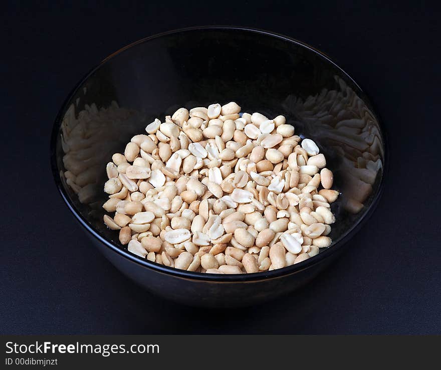 Salty dry peanut in a plate close up on a dark background. Salty dry peanut in a plate close up on a dark background