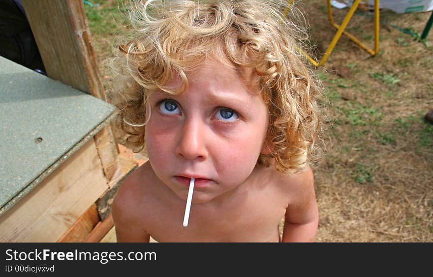 Little girl sucking her lolly and looking up. Little girl sucking her lolly and looking up