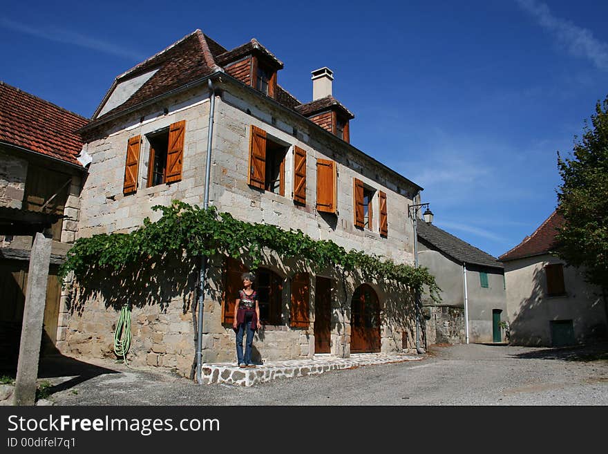 Woman standing in front of old house in correze, france