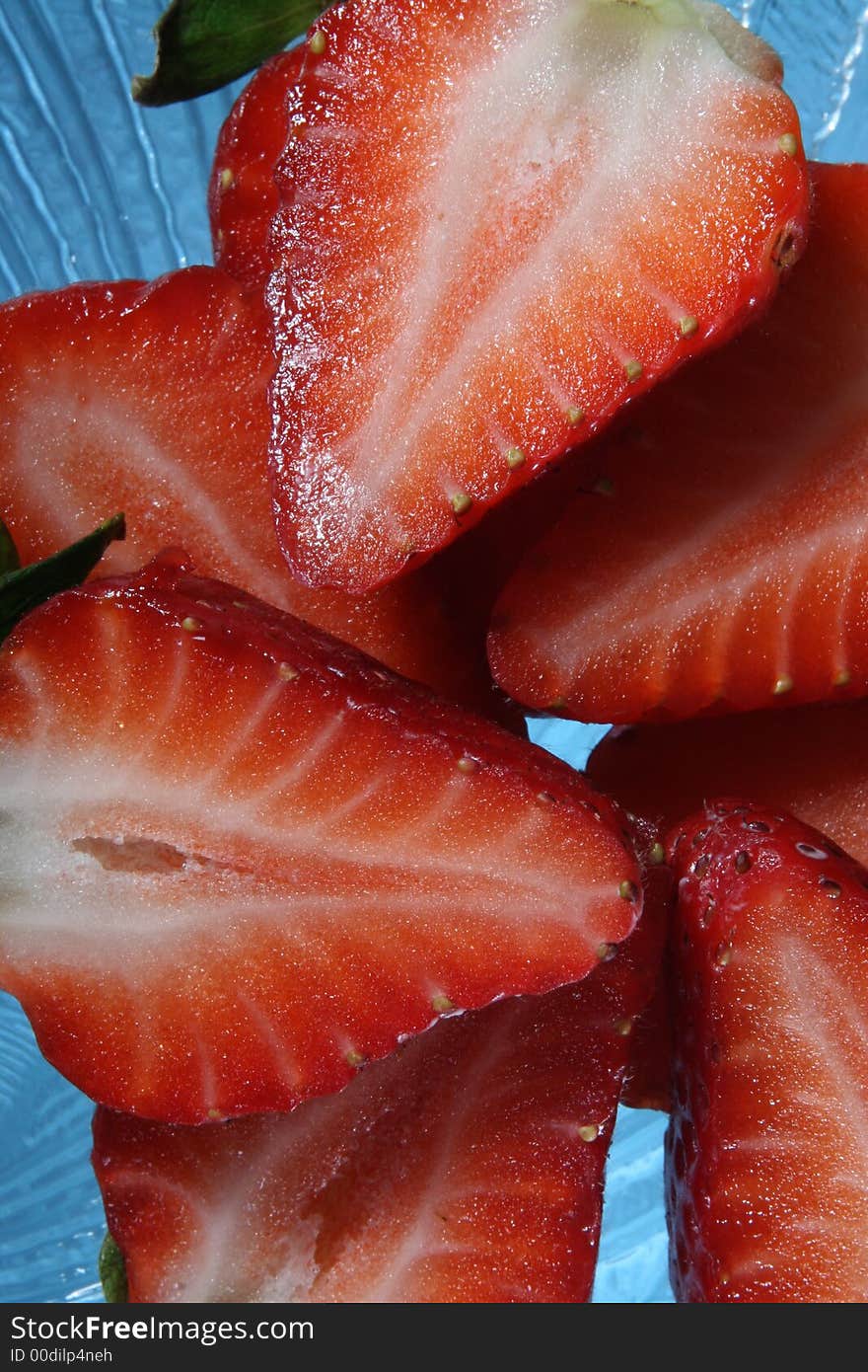 Strawberries cut in half on a clear glass plate. Strawberries cut in half on a clear glass plate