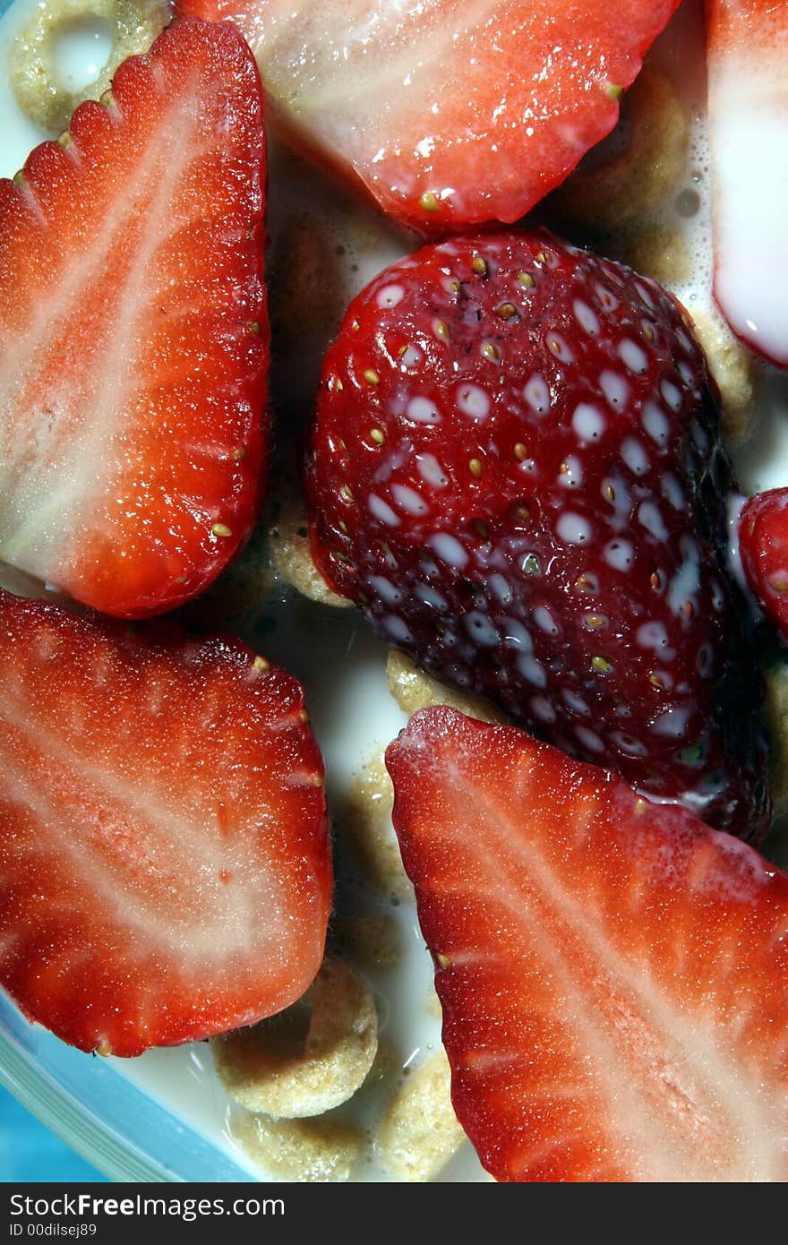 Strawberries in bowl of cereal with milk close-up on blue background. Strawberries in bowl of cereal with milk close-up on blue background