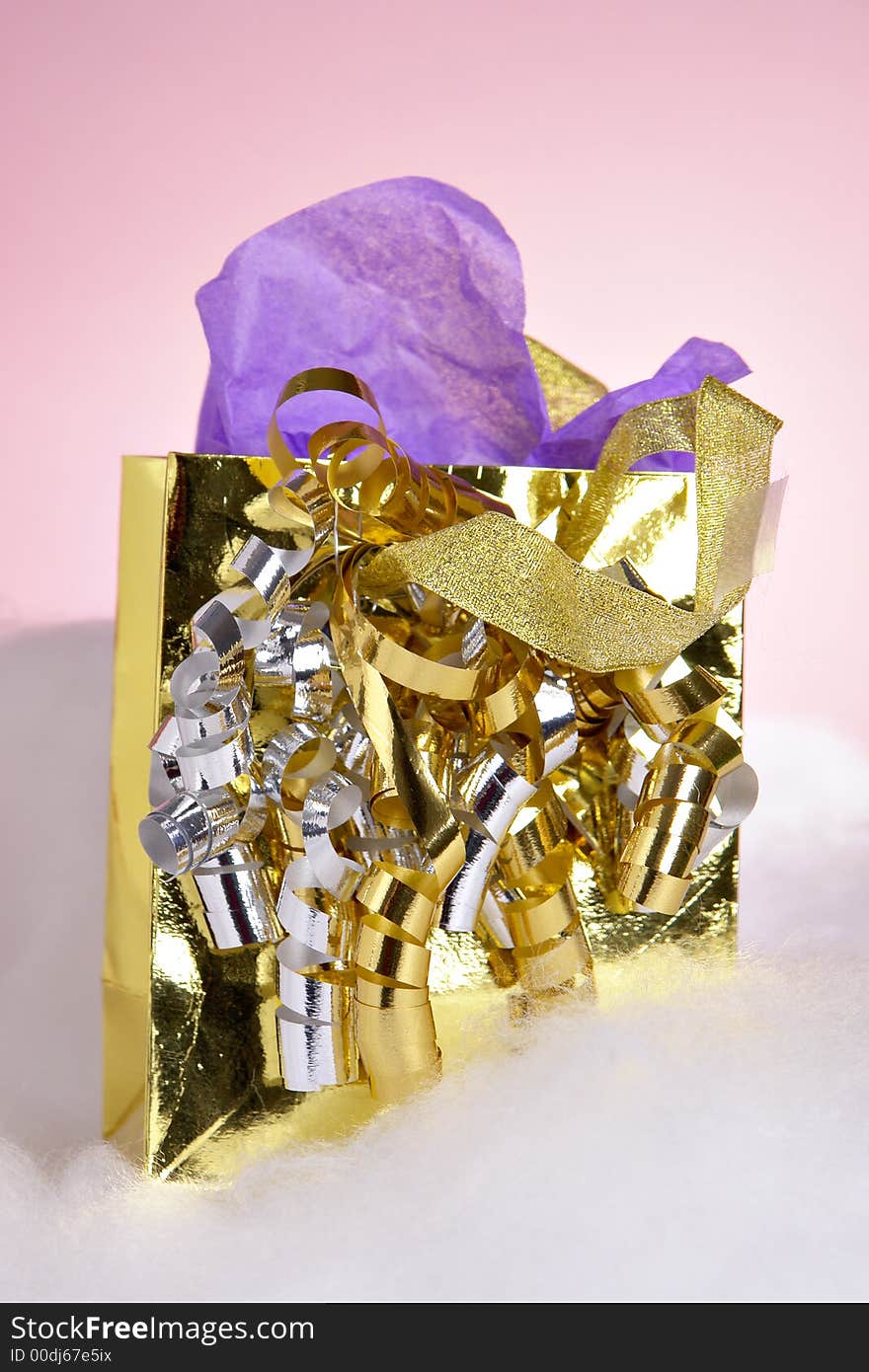 A small gold metallic gift bag with ribbons