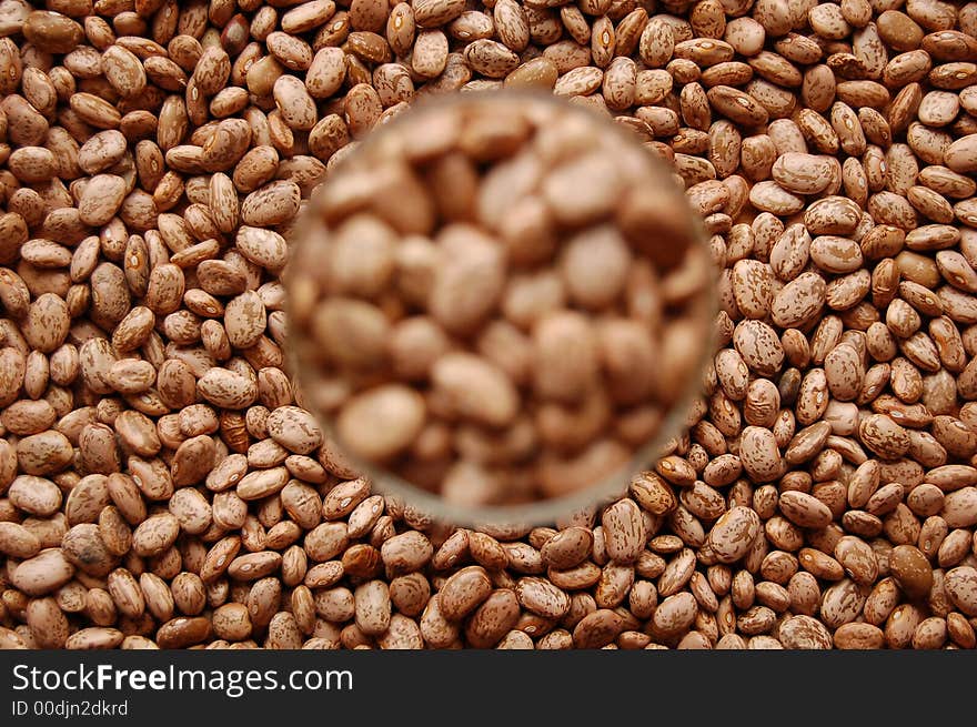 Stained beans in wine glass out of focus surrounded by other beans. Stained beans in wine glass out of focus surrounded by other beans