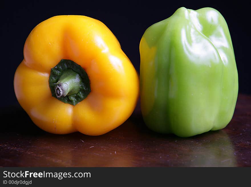 Two colorful peppers on black background