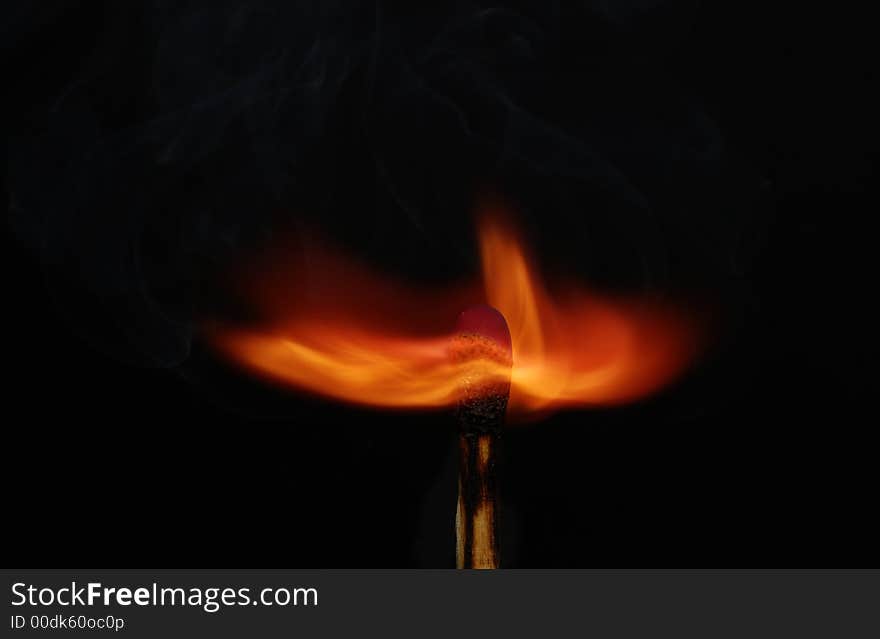 Photo of a burning match with smoke on a black background