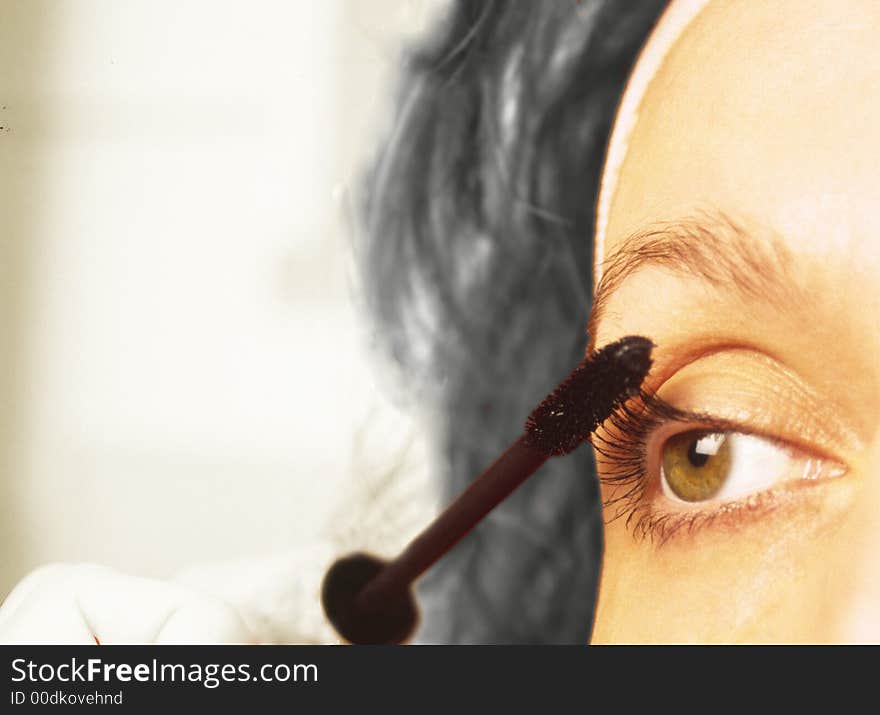 Woman does make-up for eyes on  grey background