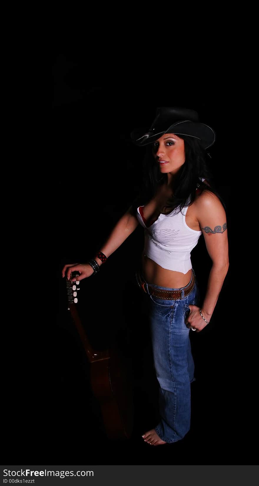 Classic country girl wearing hat with standing pose and holding her guitar. Classic country girl wearing hat with standing pose and holding her guitar