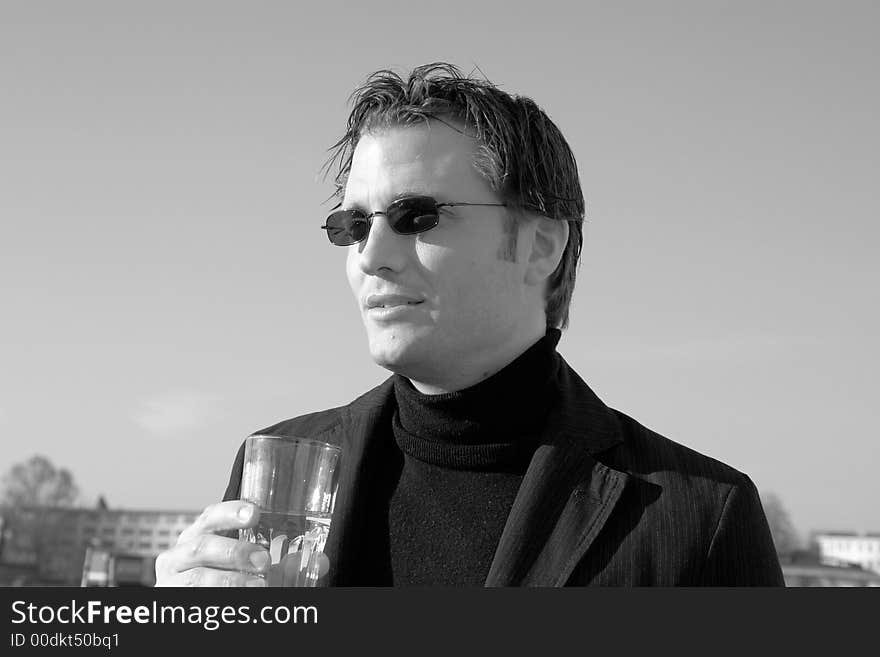 A thoughtful man looking serious and concerned. Holding a glass of water he is thinking of the climate change and the future.