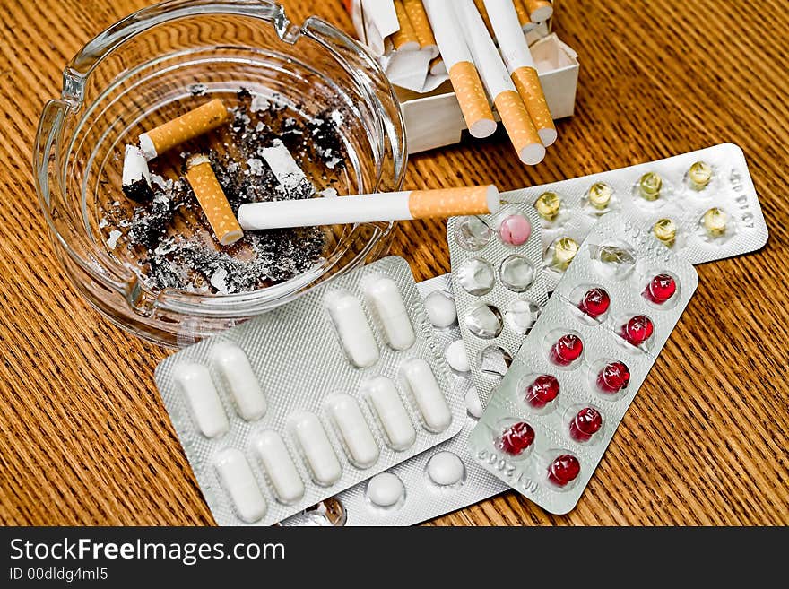 Cigarettes, ashtray, various tablets, stubs on a table, (studio,halogen light). Cigarettes, ashtray, various tablets, stubs on a table, (studio,halogen light).