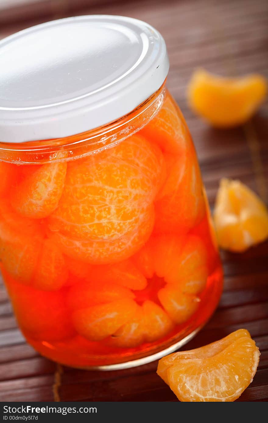 Tangerines liqueur into glass jar on the table