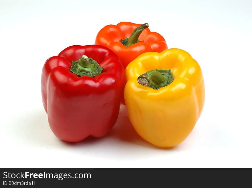 Red, orange, and yellow bell peppers on white background. Red, orange, and yellow bell peppers on white background