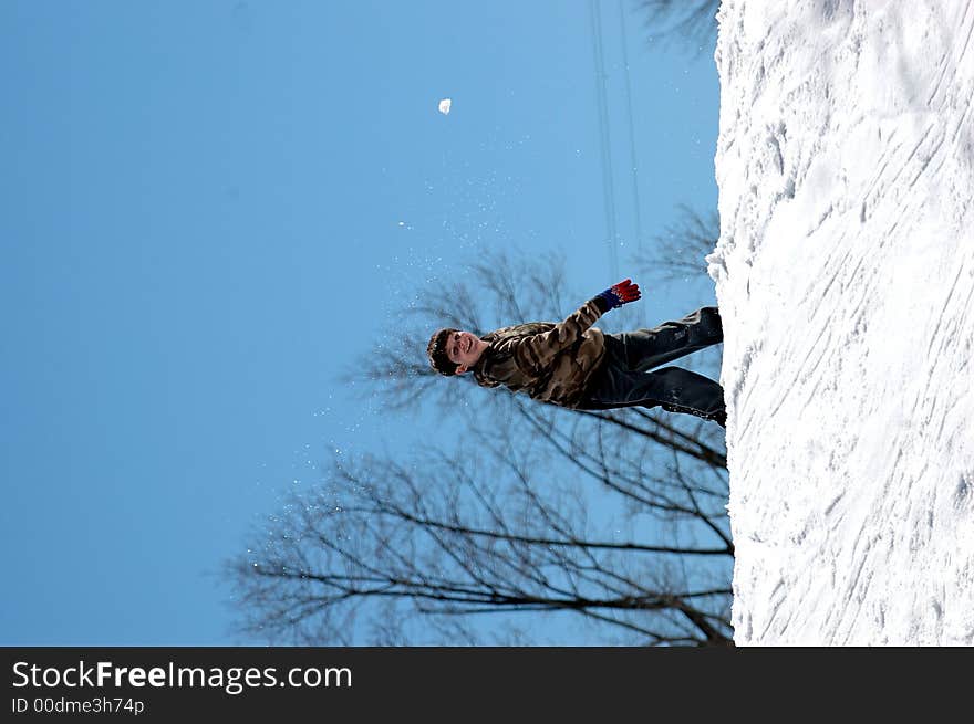 A boy at the top of a snow covered hill trowing a snowball. A boy at the top of a snow covered hill trowing a snowball