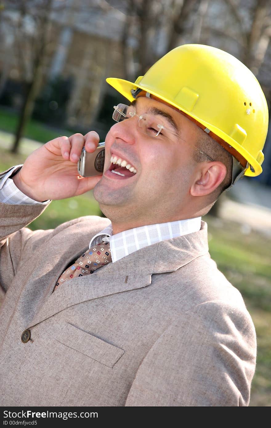 A businessman with helmet calling by mobile phone