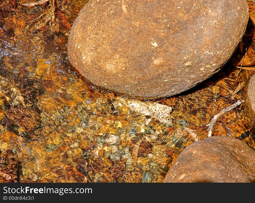 Crystal clear running water coming down from the mountains after rain into a creek showing the peddles and stones on the bottom of the creek bed