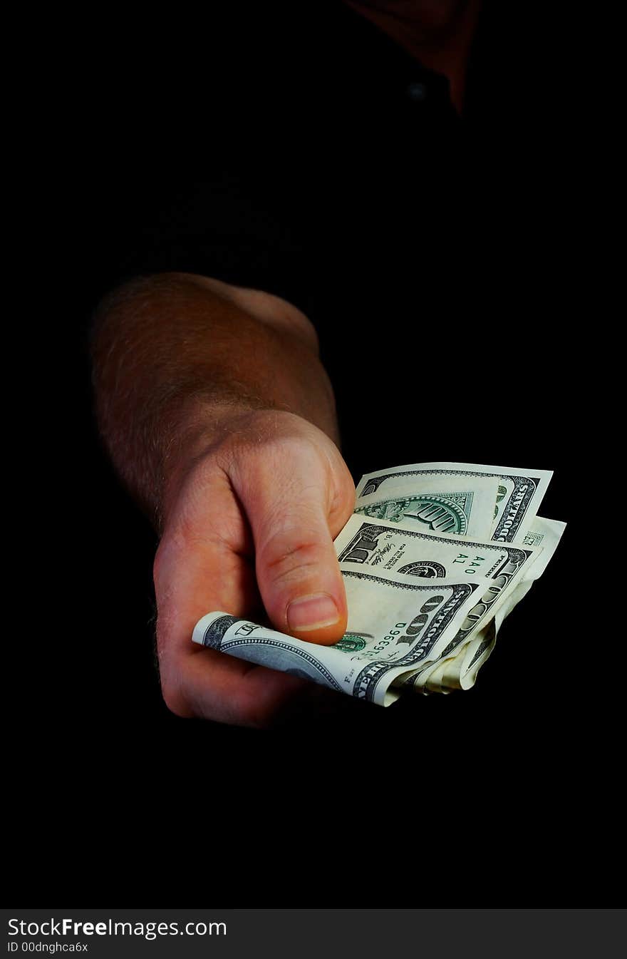 View of man’s hand coming out from the dark with a hundred dollars bills. View of man’s hand coming out from the dark with a hundred dollars bills