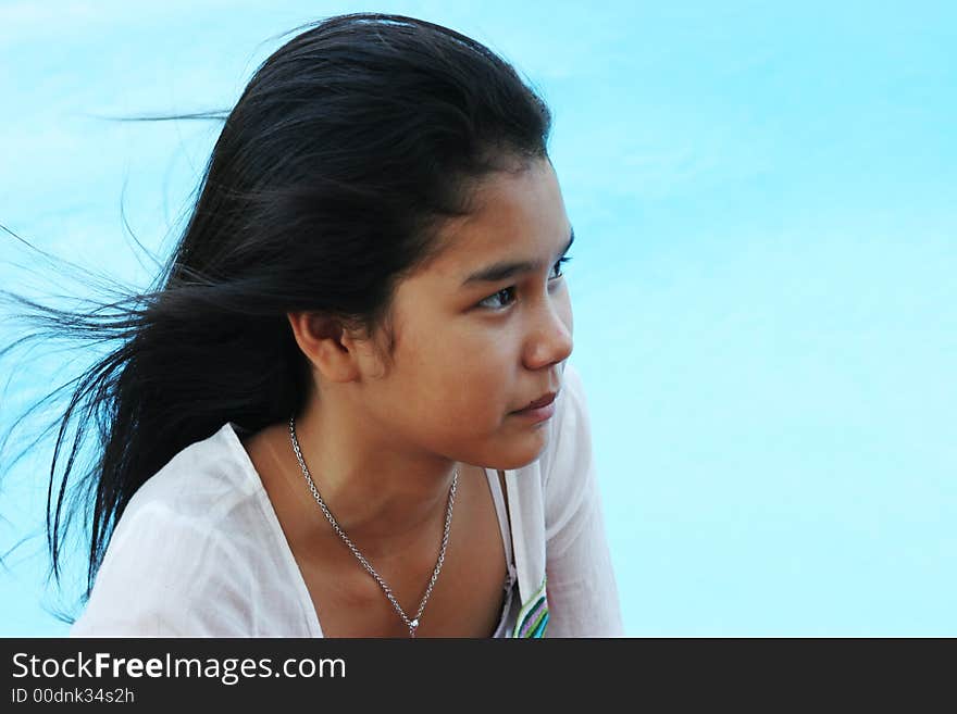 Happy girl with flowing hair relaxing by the swimming pool