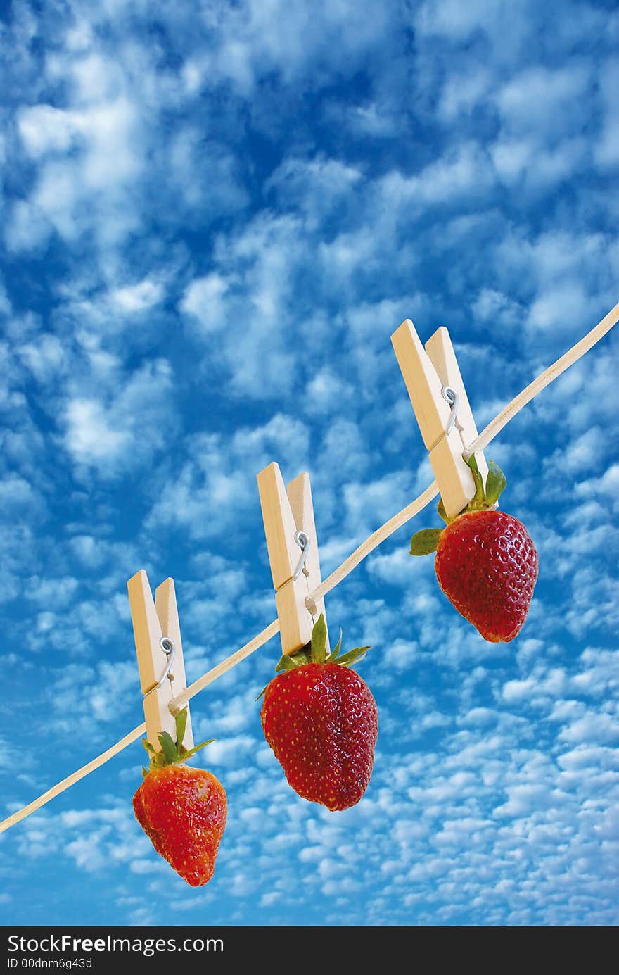 Three strawberry's hanging to dry and a cloudy sky. Three strawberry's hanging to dry and a cloudy sky