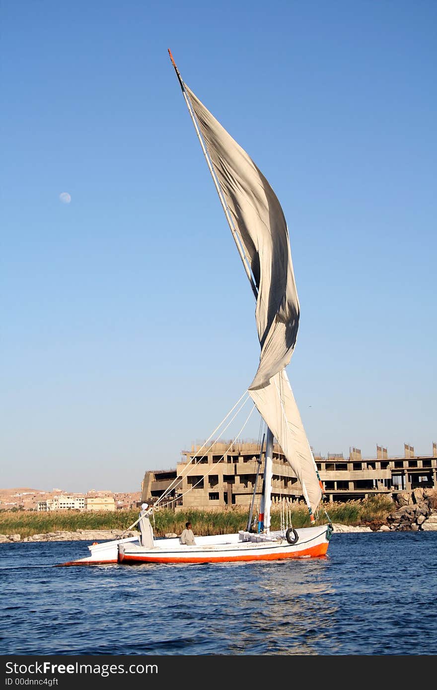 Traditional Egyptian Felucca sailing boat in river nile in Aswan southern Egypt... The moon is in the sky on the left hand side...