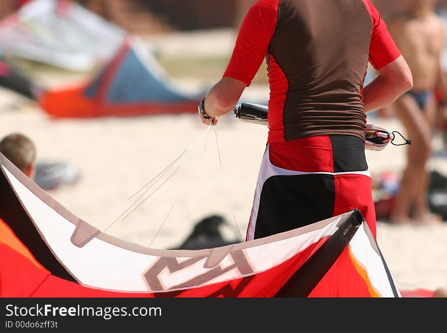 Kitesurfer prepares his equipment on the beach.